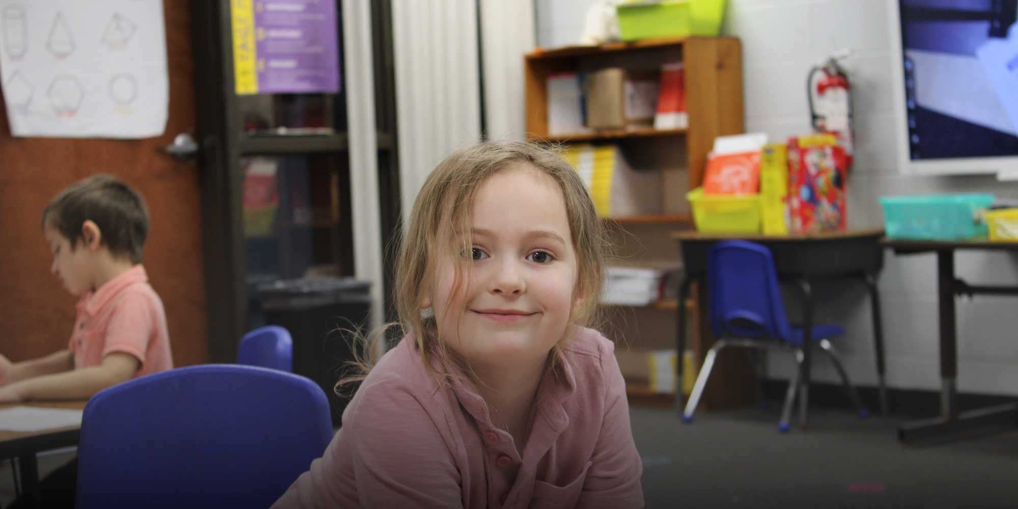Smiling student sitting at a desk in a Toledo Preparatory Academy classroom.